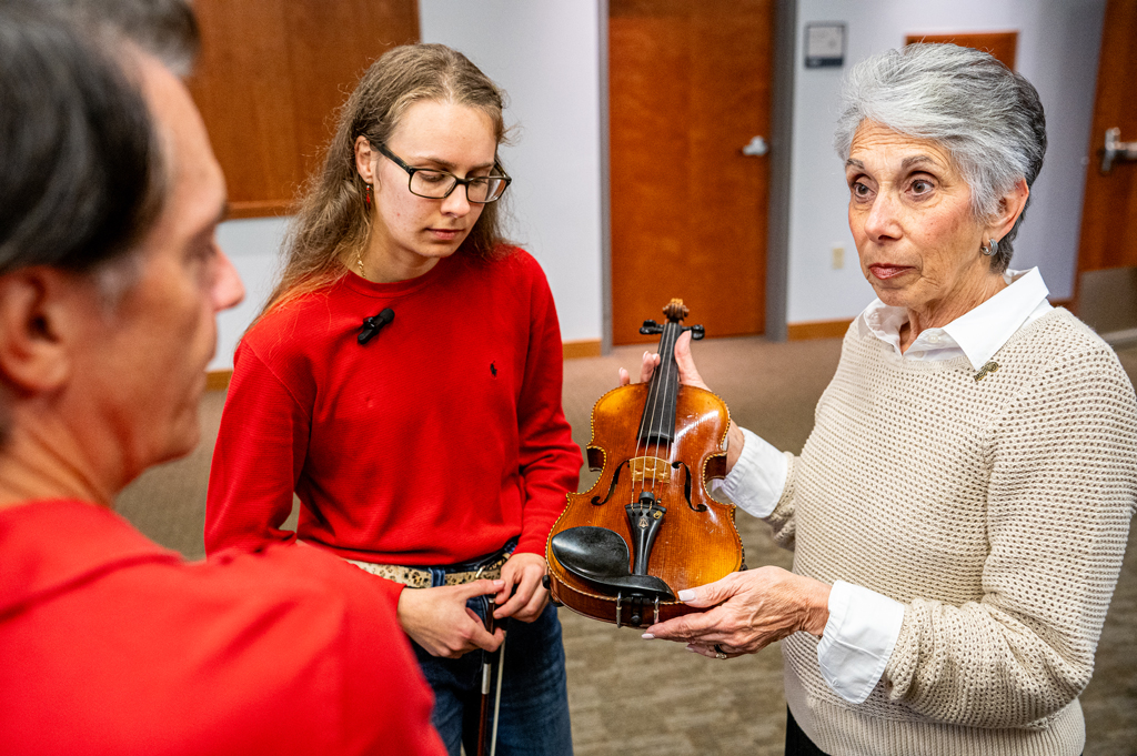 student examines one of the Violins of Hope