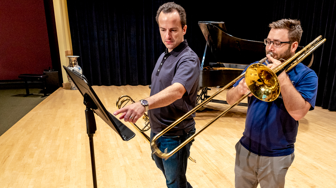 A trombone instructor gives a lesson to a student.