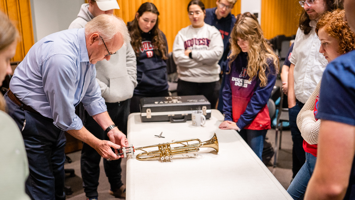 A faculty member demonstrates how to use a mouthpiece puller on a trumpet.
