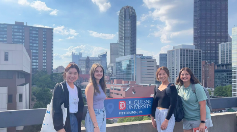 Students at selfie spot on campus next to Duquesne University sign